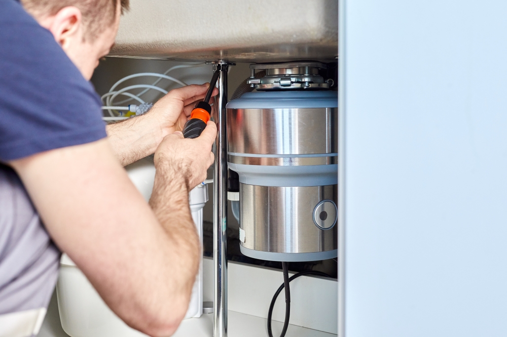 Plumber installing garbage disposal