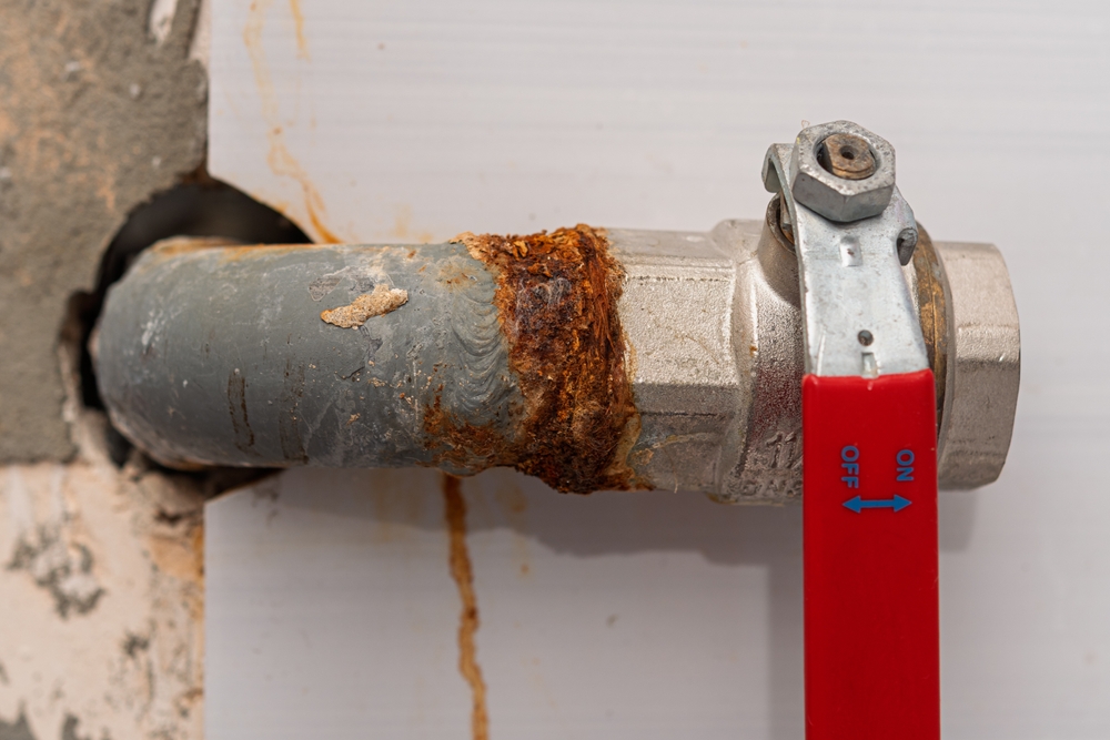 Plumber under a sink in blue overalls